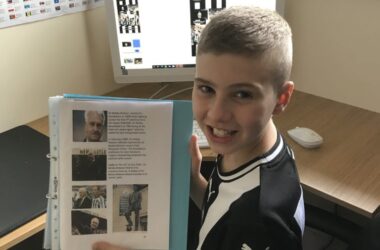 Jamie Stuart smiling holding up work.