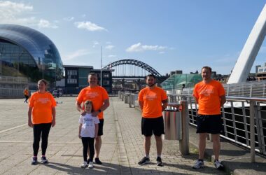 People stood smiling with the Tyne bridge behind.